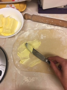 Spreading butter on kouign amann dough.